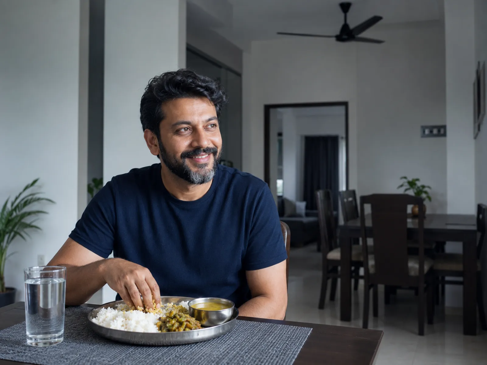 A man relaxed and comfortable at his home dining table after a home-cooked meal of rice, dal and sabzi