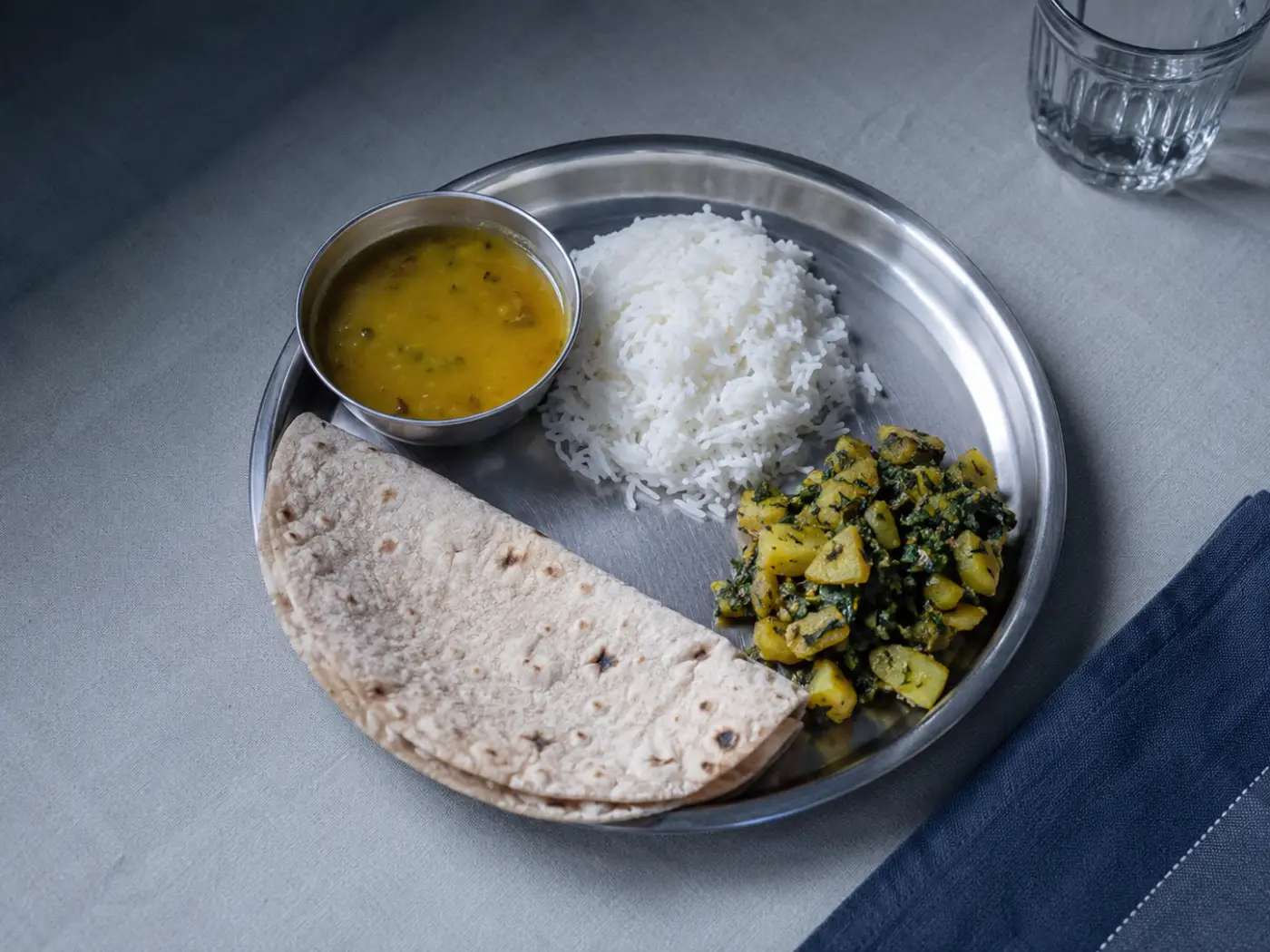 An authentic Indian home-style thali of rice, dal, roti and sabzi on a simple steel plate